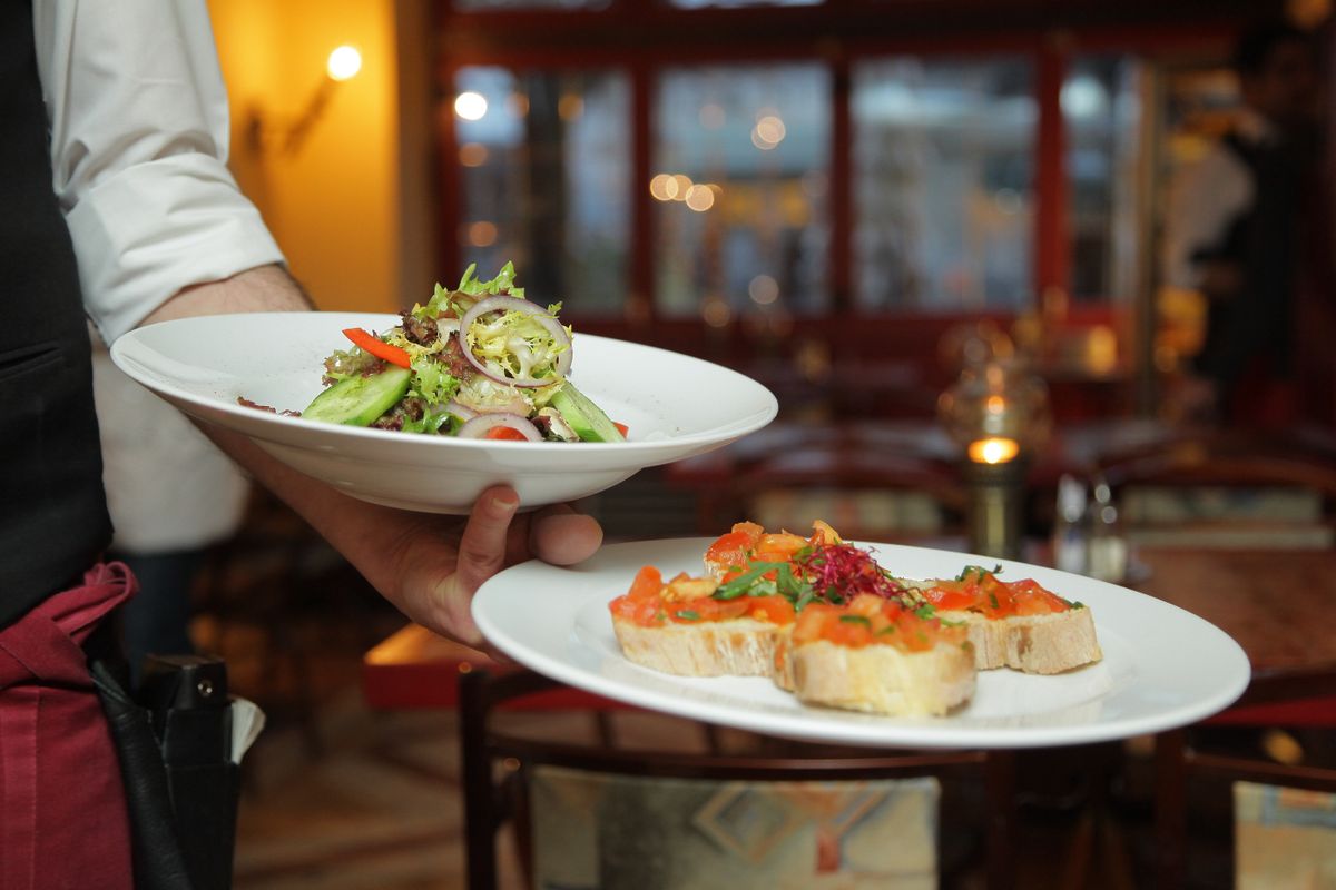 Server presenting two plated dishes
