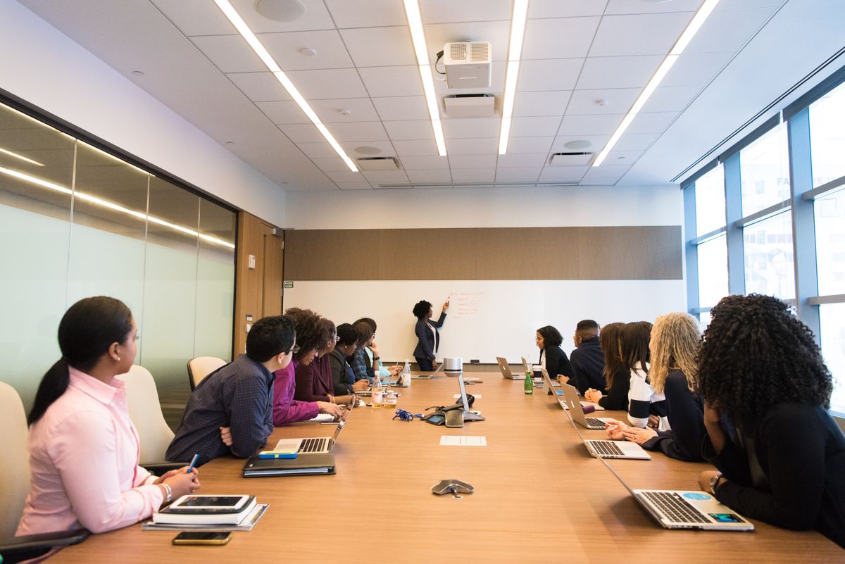 Meeting room with a long table, screen and seated attendees