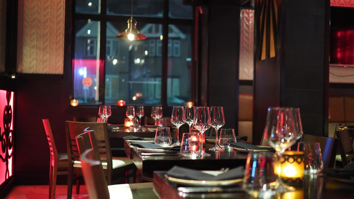 Restaurant interior at dusk with set tables and warm pendant lighting