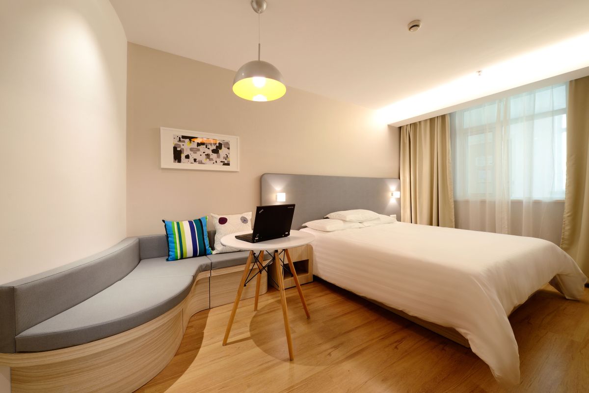 Hotel room with a made bed, work desk and warm lamp light